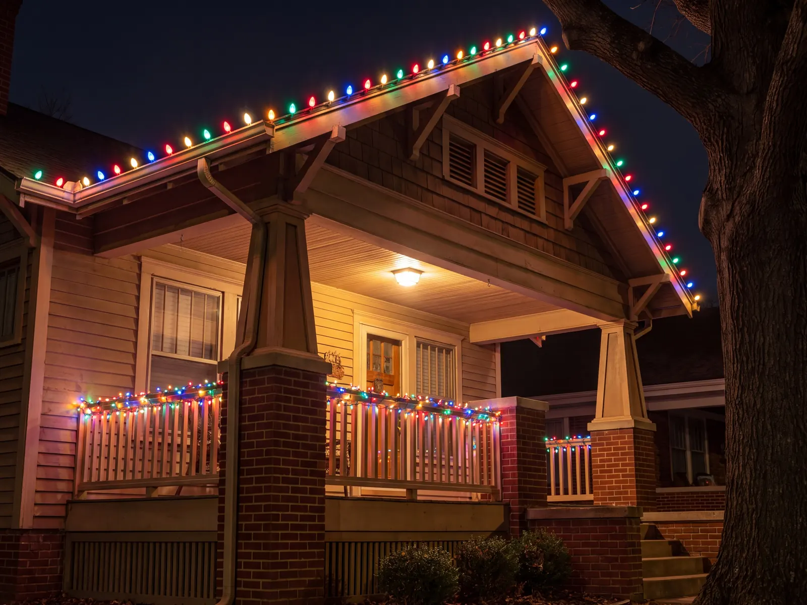 Craftsman bungalow porch at night with multicolor C9 lights along the gable and the porch railing
