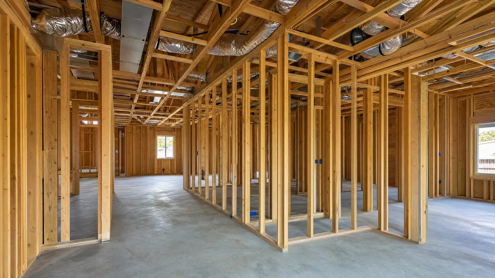A framed house with supply ducts in the ceiling joists and no drywall yet.