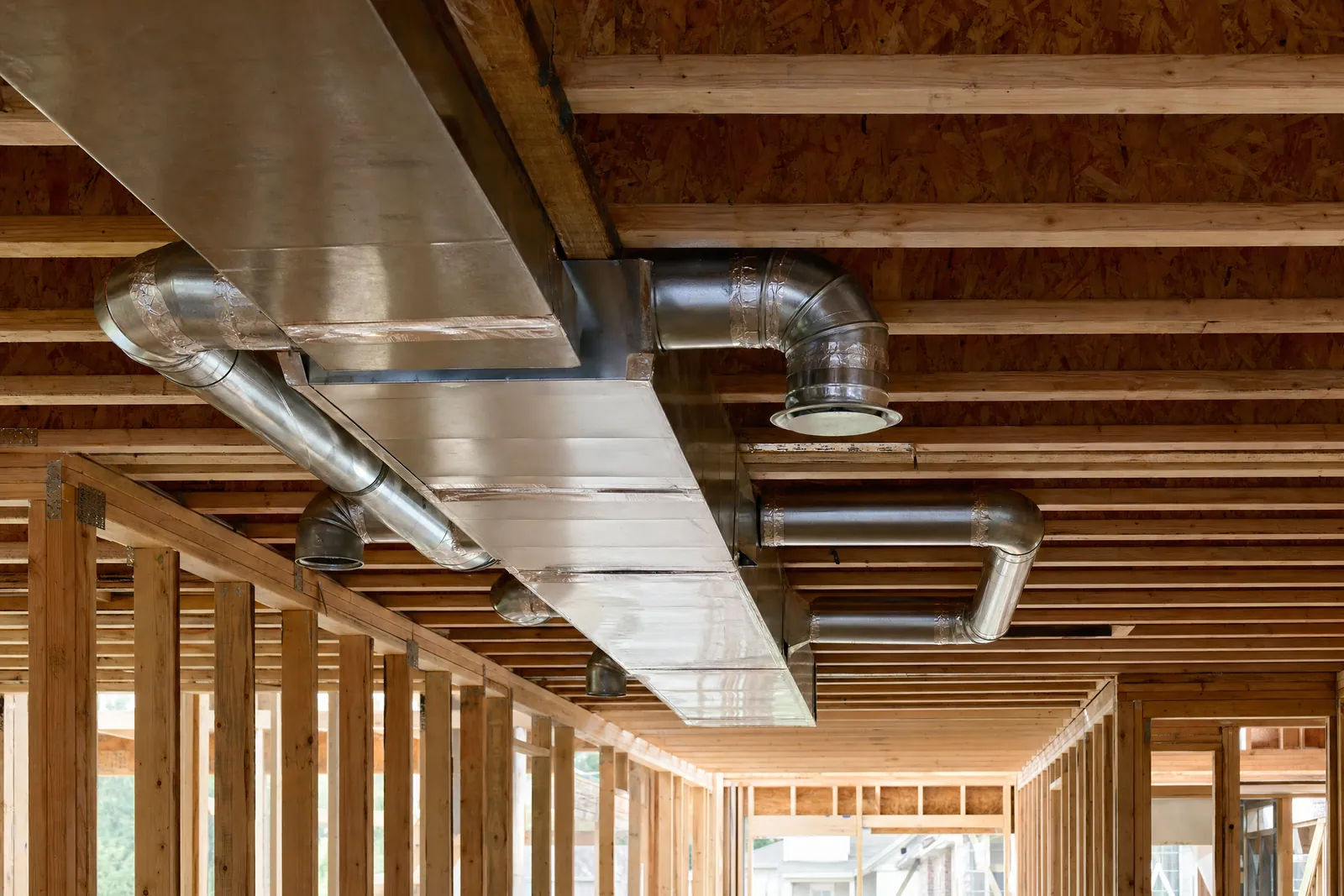 Metal duct in open floor joists of a house under construction.